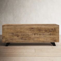 a wooden box sitting on top of a hard wood floor next to a white wall