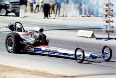 a man driving a racing car on top of a race track with people watching from the sidelines