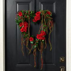 a wreath with red roses hanging on the front door