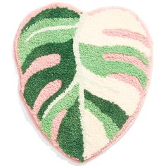 a pink and green heart shaped rug with a large leaf on the front, sitting on a white surface