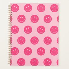 a pink notebook with smiley faces on it