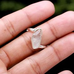 a person's hand is holding a ring with a large stone in the middle