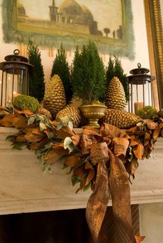 a mantel decorated with pine cones and greenery