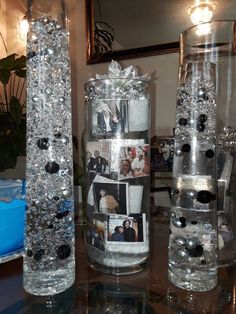 three clear vases with pictures on them sitting on a table in front of a mirror