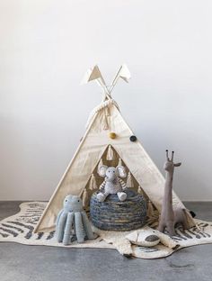 a teepee tent with two stuffed animals on the floor next to it and an animal figurine