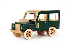 a green wooden toy truck with stacks of wood on the front and back wheels, against a white background