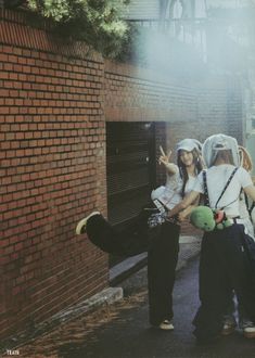 two girls standing next to each other near a brick wall