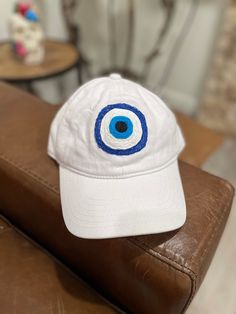 This hand made, one of a kind, embroidered white baseball cap features one evil eye.  I don't make the same thing more than once, so get it if you like it. I priced the items based on the time I spent making them and the cost of the hats themselves.  Care instructions: hand wash in cold water, hang by brim to dry. White Baseball Cap, The Evil Eye, Greek Evil Eye, Trucker Cap, Evil Eye, Baseball Cap, Caps Hats, Trucker Hat, Cold Water