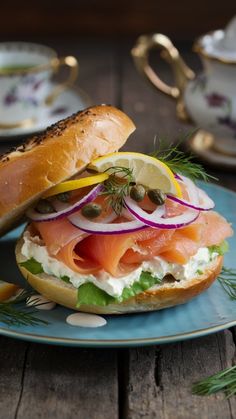 a bagel sandwich with salmon, lettuce and onions on a blue plate