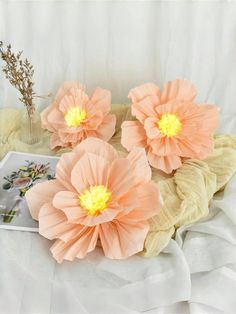 three paper flowers sitting on top of a bed