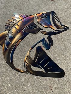 a metal fish sculpture sitting on the ground