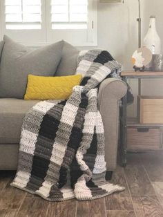 a gray couch with a black and white blanket on it next to a yellow pillow