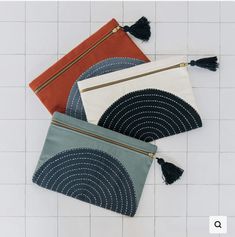 three zippered pouches with tassels on white tiles