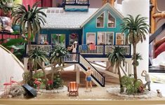 a toy house with palm trees and people in it