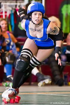 a woman rollerblading down a track in a blue outfit and black knee pads