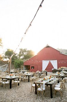 tables and chairs are set up in front of a barn