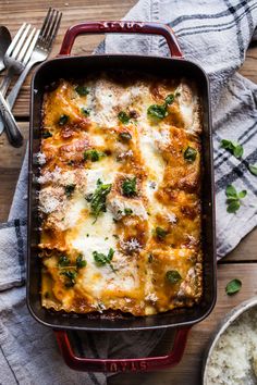 a casserole dish with cheese and spinach in it on a wooden table