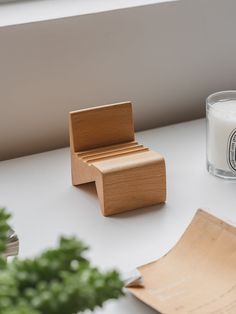 a small wooden chair next to a candle and some papers on a white counter top