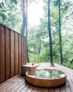 a hot tub sitting on top of a wooden deck next to trees in the woods