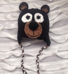 a crocheted bear hat with big eyes on top of a white bed sheet