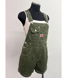 Short overalls with a multi pocket bib and logo patch detail. Traditional straps with clasp closures. Pockets on the front and back with button closures at the sides. Looks great paired with crop tops. SMALL: Waist: 26" | Hips: 40" | Inseam: 3.5" MEDIUM: Waist: 28" | Hip: 42" | Inseam: 3.5" LARGE: Waist: 30" | Hip: 44" | Inseam: 3.75" Material | 100% Cotton (Non-Stretchy Canvas/Denim) Care Instructions | Machine Wash or Hand Wash Cold  Measurements | 30" or 76 cm Top to Bottom 3.5" or 9 cm Inseam [Measured on a size Small] Model is 5'8 and wearing a size Small SMALL CUSTOMER REVIEWS 1. I'm 5'4 about 120 pounds and I ordered a small in the navy. They fit perfectly! I would recommend getting the size you usually wear. The fabric and stitching feel high quality. 2. The overalls are just great Southern Clothes, Grunge Overalls Outfits, Green Overalls Outfits, Short Overalls Outfit, Short Jumpsuit Outfit, Overall Shorts Outfit, Green Overalls, Overalls Outfits, Work Overalls