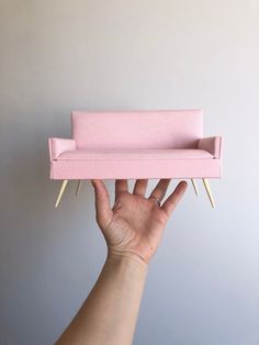 a person holding up a pink couch with nails sticking out of it's sides