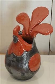 an orange and silver vase sitting on top of a white table next to a wall