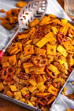 a tray filled with cheetos and pretzels next to a colander