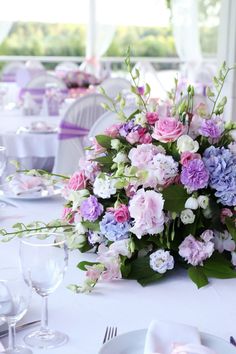 an arrangement of flowers on a table at a wedding reception with white and purple linens