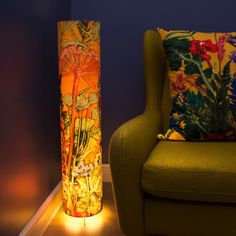 a lamp that is sitting next to a green chair and a pillow on the floor