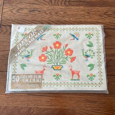 an embroidered placemat with flowers and birds in it on a wooden tablecloth pad