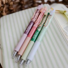 four pens sitting on top of an open book