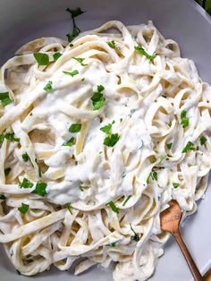 a white bowl filled with fettuccine alfredo and topped with parsley