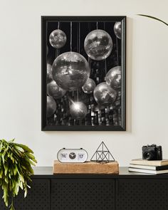 a black and white photo of disco balls hanging on a wall above a table with a plant