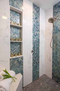 a bathroom with blue and white tiles on the walls, shelves in the shower area