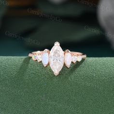 an engagement ring with three pear shaped white opal stones on the sides and two diamonds in the middle