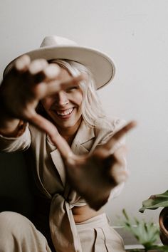 a woman wearing a white hat sitting on top of a wooden table next to a potted plant