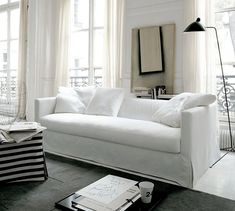 a living room with white furniture and large windows