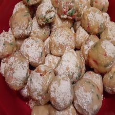 a red bowl filled with cookies covered in powdered sugar