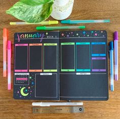 an open planner sitting on top of a wooden table next to markers and pencils