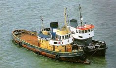 two tug boats sitting in the water next to each other on top of one another