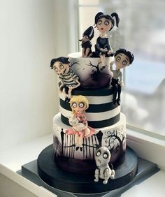 a three tiered cake decorated with figurines on it's sides and black and white stripes