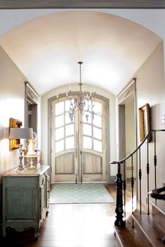 an entry way with a chandelier, table and stairs leading to the front door