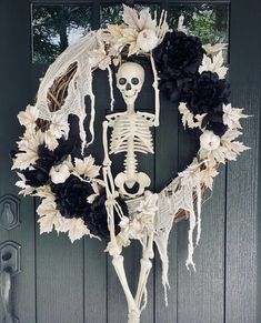 a skeleton wreath with black and white flowers hanging on the front door for halloween decoration