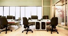 an empty office with desks and chairs in front of large windows that look out onto the outside