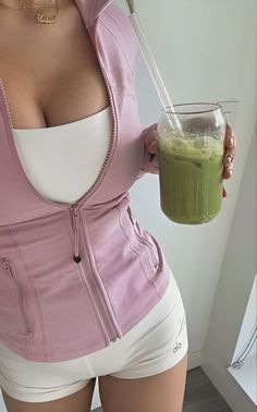 a woman is holding a green smoothie in her hand