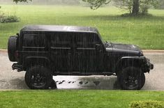 a black jeep is parked in the rain