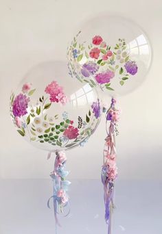 two clear balloons with flowers painted on them