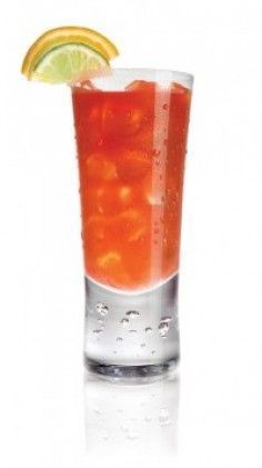 a tall glass filled with ice and orange slices on the rim, next to a lime slice