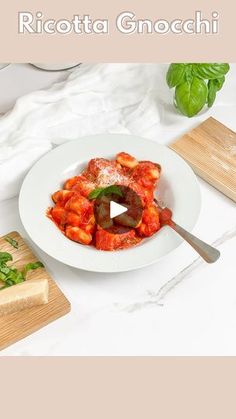 a white plate topped with pasta and sauce on top of a table next to cutting boards